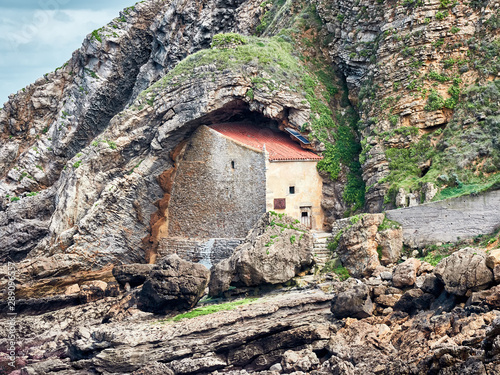 Old hermitage built on a rock, on the beach of Santa Justa, in the village of Ubiarco, Santillana del Mar, Cantabria, Spain photo