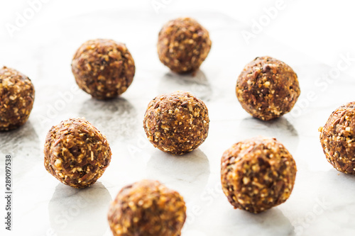 Energy protein balls with healthy ingredients on marble table. Home made with dates, peanut butter, flax and chia seeds, oats, almond and chocolate drops. Food modern pattern on marble table