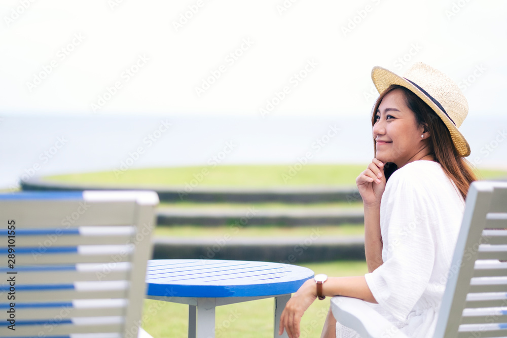 A beautiful asian woman enjoy sitting and relaxing on the bench by the sea