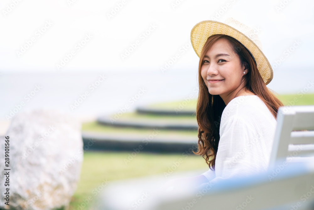 A beautiful asian woman enjoy sitting and relaxing on the bench by the sea