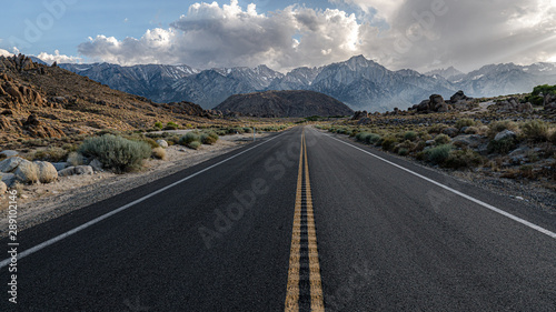 lange, einsame Straße vor schneebedeckten Bergen