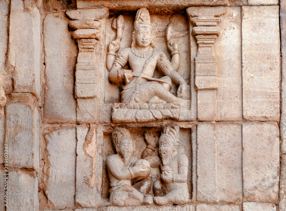 Indian art on facade of temple with Shiva Lord and ancient hindu people. South Indian landmark, the 7th century carvings of Pattadakal, India. UNESCO World Heritage site