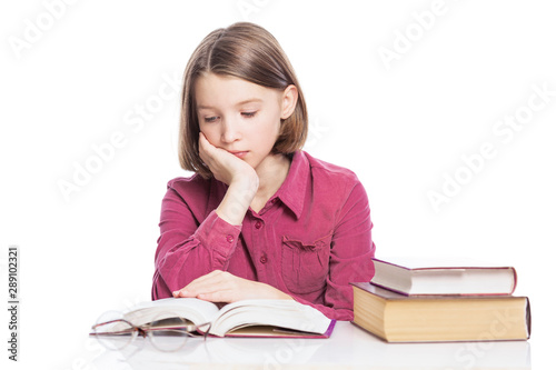 Tired teen girl sitting at a table with books. Isolated over white background.