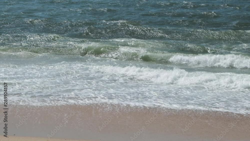 Slow motion white surf waves breaking on sandy beach in summer Slow motion white surf waves breaking on sandy beach in summer