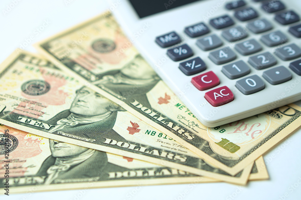 Calculator on ten dollars banknotes on a white background. Concept of Calculation of income and expenses Calculator on ten dollars banknotes on a white background. Concept of Calculation of income and expenses