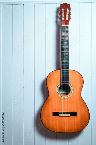 Guitarra criolla sobre pared de madera celeste
