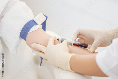 Doctor's hands take blood from a vein from a patient sitting in a chair. Blood test concept and detection of diseases