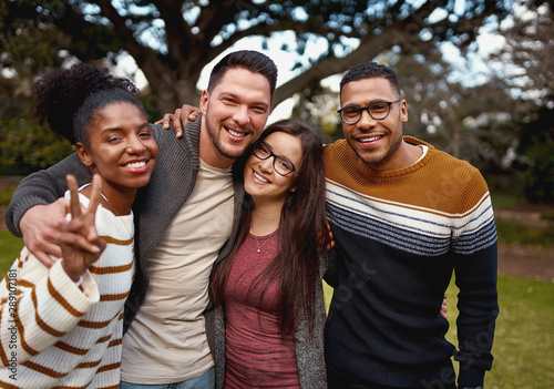 Group of young multi racial african american friends standing and smiling together in the park - dressed warm
