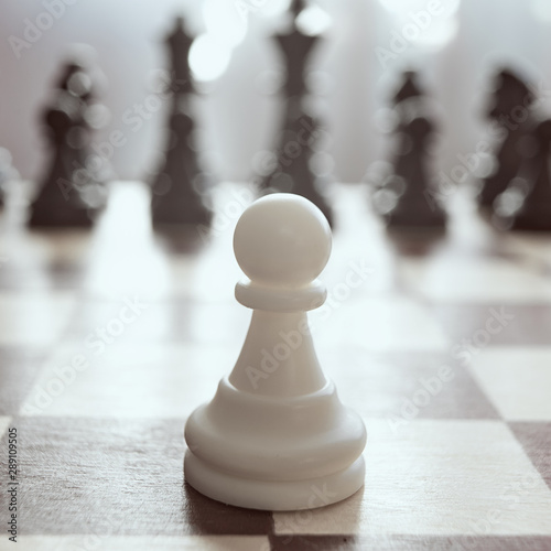Single pawn against many enemies as a symbol of difficult unequal fight or struggle of minorities. Background in blur.