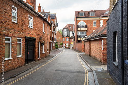 Narrow street lined with traditional brick residential buildings on a cloudy spring day. Eaton, England, UK. © alpegor