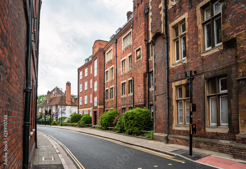 Empty narrow street lined with old brick apartment buildings on a cloudy spring day. Eaton, England, UK.