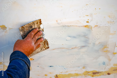 A Man repairing or renovation wooden fishing boat surface.