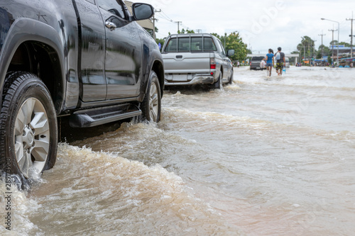 Cars driving on a flooded road, The broken car is parked in a flooded road. .
