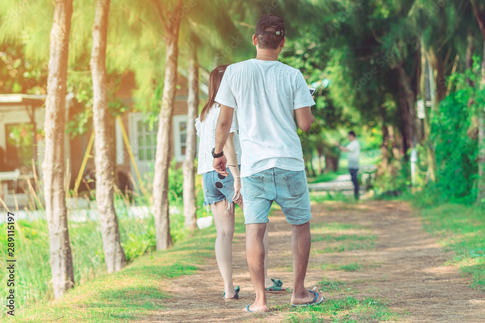 Couple walking and taking photos under the pine trees in the public park.