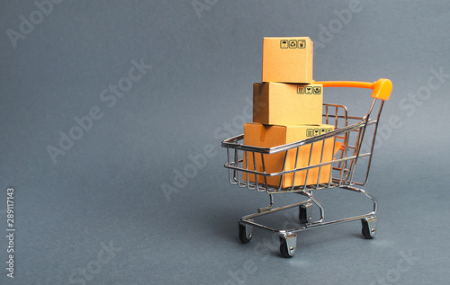 A pile of cardboard boxes in a supermarket trolley. concept of shopping in the online store . E-commerce, sales and sale of goods through online trading platforms. Consumer society. Purchasing power