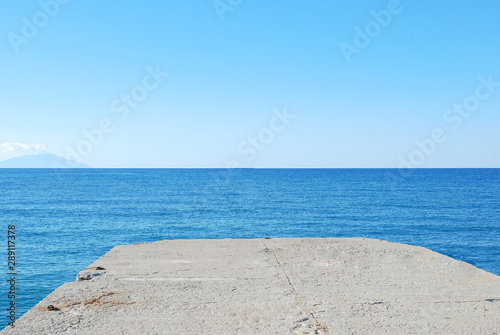 Concrete pier with a blue wavy sea