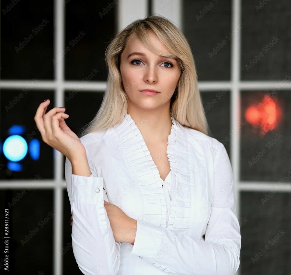 Portrait of a pretty manager blonde girl at work in a white blouse in the office at the table. Right in front of the camera in various poses. Portrait of a pretty manager blonde girl at work in a white blouse in the office at the table. Right in front of the camera in various poses.