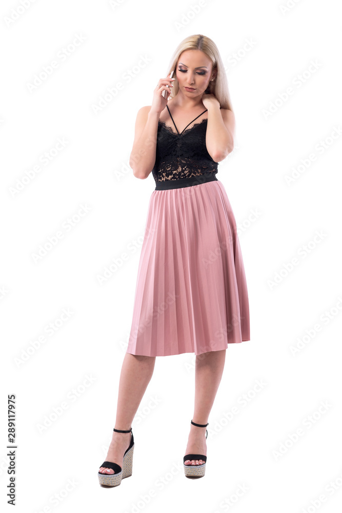 Serious worried pretty blond hair woman talking on the cellphone looking down. Full body isolated on white background. Serious worried pretty blond hair woman talking on the cellphone looking down. Full body isolated on white background.