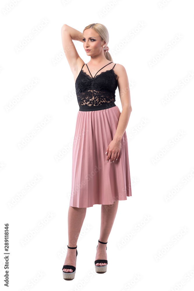Beautiful confident blonde woman fashion model holding hair in pink skirt looking away. Full body isolated on white background.