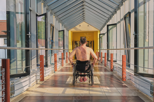man in a wheelchair rides along the corridor to a hydropathic center on Lake Heviz in Hungary, Swimming pool for disabled people access to the pool
