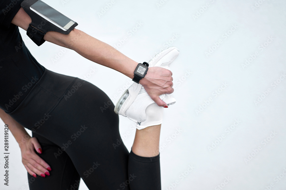 Closeup view. Slim girl wearing black sportswear stretching on white wall background. Concept active and healthy life.