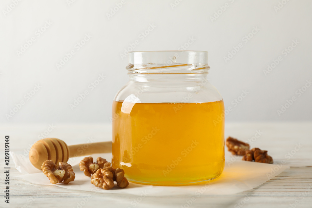 Walnuts, dipper, parchment and glass jar with honey on white background, copy space Walnuts, dipper, parchment and glass jar with honey on white background, copy space