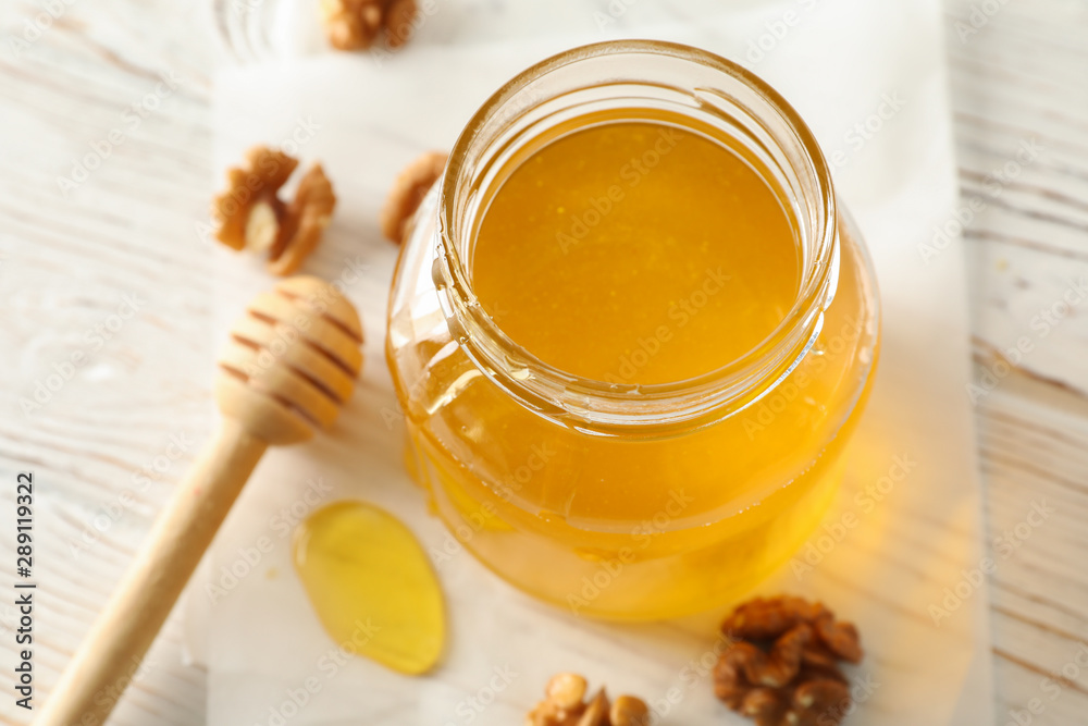 Walnuts, dipper, parchment and glass jar with honey on white background, closeup Walnuts, dipper, parchment and glass jar with honey on white background, closeup