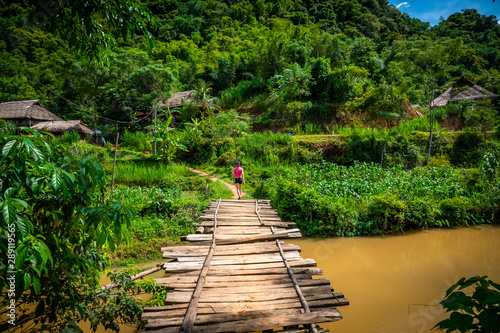young woman hiking on a wooden bridge in Pu Luong, rural area close to Mai Chau, Vietnam. 