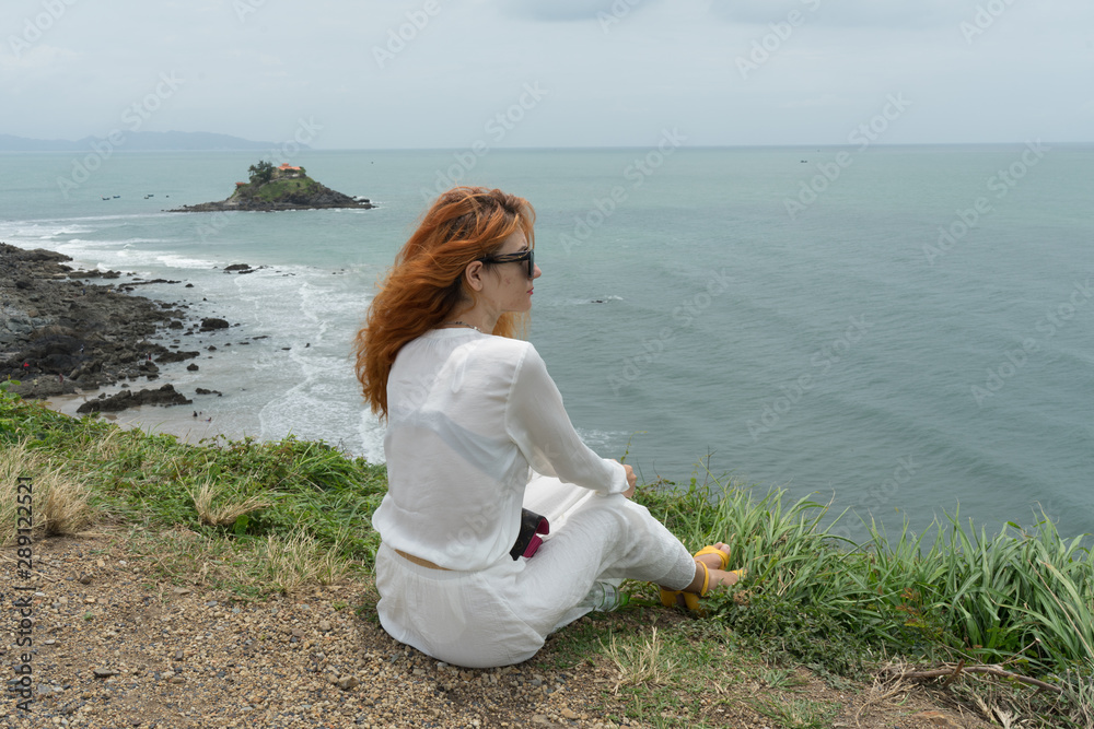 Red haird girl in long white skirt  traveler in nature looking to beautiful view and small island in Vung Tau.Relax time on holiday concept travel .