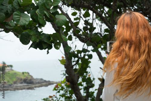 Red haird girl in long white skirt  traveler in nature looking to beautiful view and small island in Vung Tau.Relax time on holiday concept travel . photo