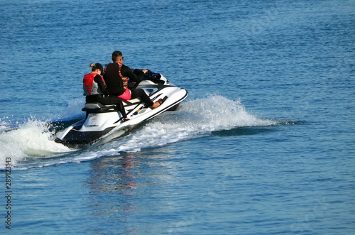 Young couple riding tandem on a speeding jet ski