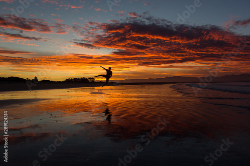 silhouette of a young man jumping on the beach in nelson during sunset on Tahunanui Beach at Nelson, New Zealand © Martin