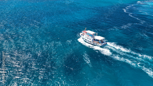 Aerial drone photo of picturesque and traditional tourist vessel cruising in famous beaches of Koufonisi island, Small Cyclades, Greece © aerial-drone