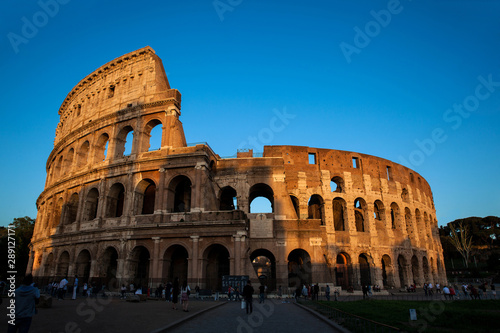 Tourists visiting the famous Colosseum under the beautiful light of the golden hour in Rome
