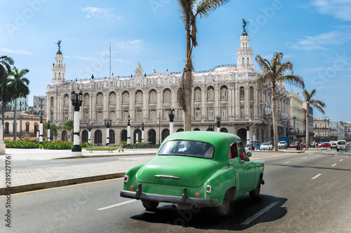 Pphotograph of a vintage green car on the street of downtown Havana: in the background blue sky with few clouds and the tipical palms of Cuba © Enrico Tricoli