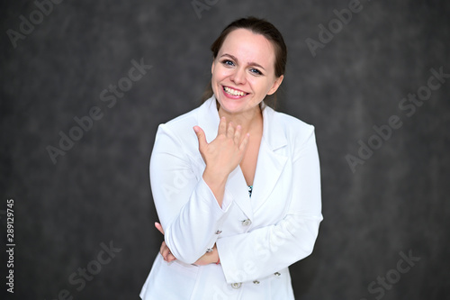 Business Portrait of a pretty female manager on a gray background in a white business suit. Standing right in front of the camera in various poses.
