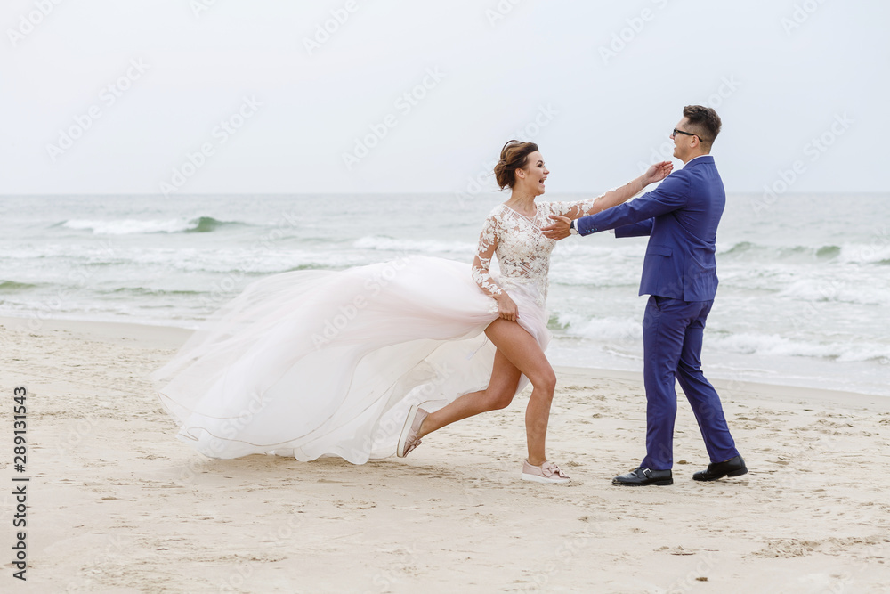 The groom whirls his bride on the beach