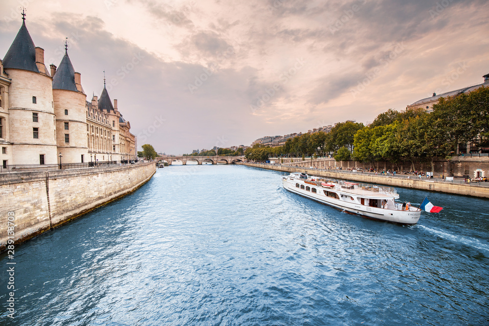 Obraz premium 26 July 2019, Paris, France: City skyline with famous building Conciergerie which used to be a prison with a bridge over the river Seine and cruise ship in Paris