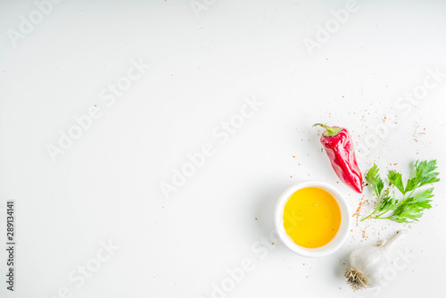 Fototapeta Naklejka Na Ścianę i Meble -  Herb and spices cooking background. Olive oil, salt, garlic, parsley, hot red peppers chili, for cooking  homemade dinner. On a white background, copy space top view
