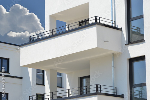 Moderne Betonbalkone mit beschichtetem Metall-Geländer an Neubau-Mehrfamilien-Hausfront mit Metall-Attica