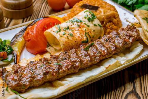 Photos lula kebab spicy with vegetables in Turkish on the board