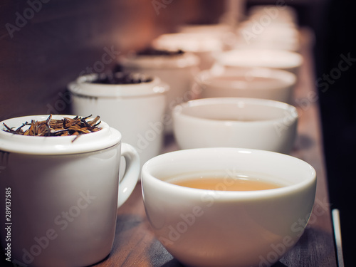Chinese tea in white tea pot and cups with the black tea leaves, Close up and selective focus image.