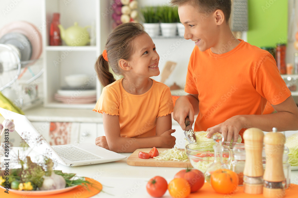 Cute brother and sister cooking together in kitchen