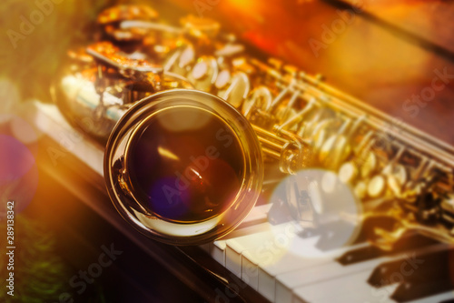close up of alto saxophone on the Piano Keys with Christmas tree and decoration light, in the night of Christmas season, Christmas background