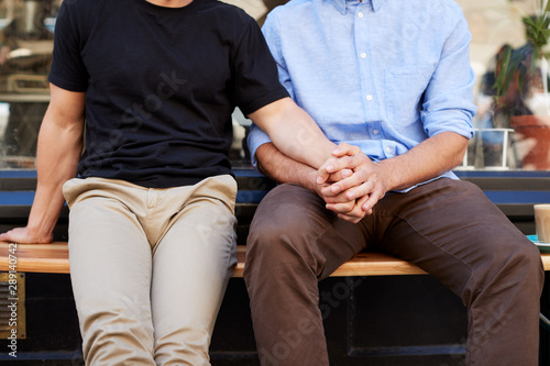 Close Up Of Male Gay Couple Sitting Outside Coffee Shop Holding Hands