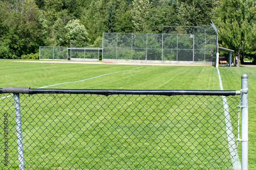 Empty baseball or softball diamond from the back fence and foul line looking towards the grass and trees in Whistler, British Columbia, Canada.