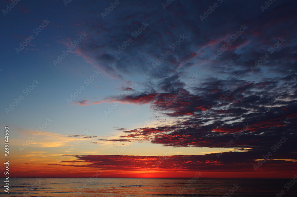 Vibrant dramatic sunset with brightly colored clouds over the Baltic Sea in Lithuania, Europe.