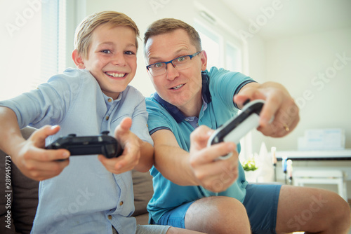 Happy young father and his son playing computer games with controllers very emotional