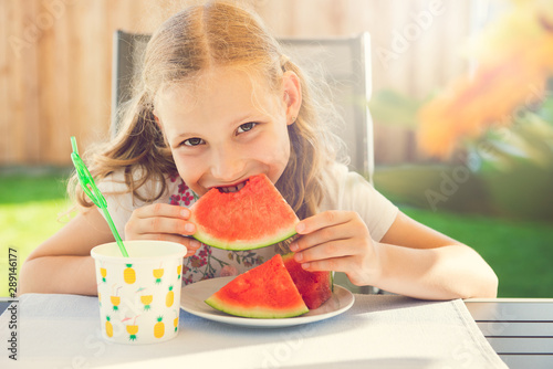 Portrait of happy cute little girl eating sweet red watermelonin garden