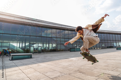 Afro man skateboarder flies in air on skateboard